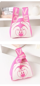 Detail view of pink knitted tote bag with LOVE heart pattern on minimalist shelf