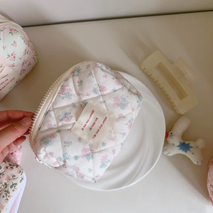 Close-up of pink floral quilted makeup bag with resin zipper and French label