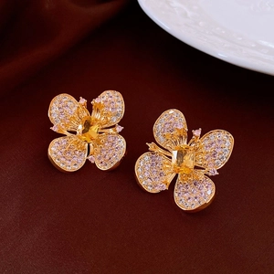 Macro detail of gold flower earrings with pink diamonds and a yellow crystal center