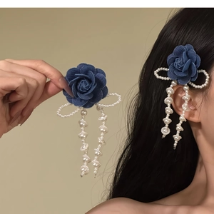 Dettaglio fermaglio per capelli rosa in denim blu con fiocco di perle e lunghe nappe