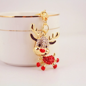 Golden Christmas reindeer keychain with red and white crystals on a white surface