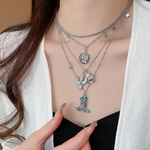 Detail of layered silver necklace featuring western cowboy boot and cactus charms