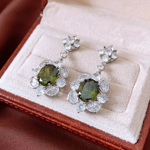 Close-up of olive green flower drop earrings with zircon crystals in a jewelry box