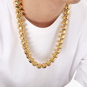Detail of chunky gold skull link necklace in punk style worn on a white t-shirt