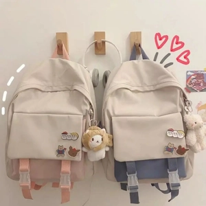 Close-up of minimalist school backpack with cute decorative badges and plush charms