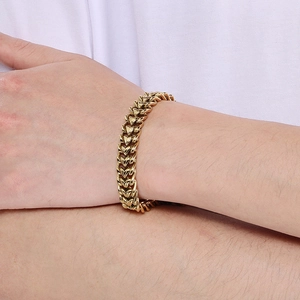 Dettaglio di un bracciale a maglia dragon dorata indossato su un polso maschile
