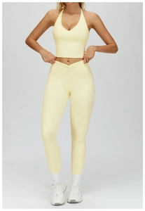 Detail of high waisted V-shaped yoga leggings and halter V-neck sports top in light yellow