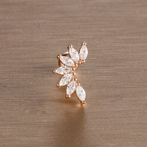 Macro view of rose gold leaf ear stud with marquise-cut zircons on brushed metal