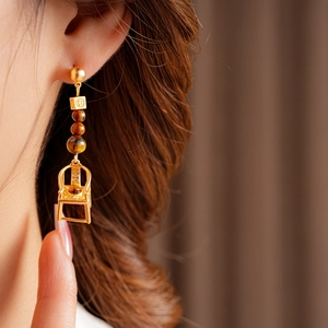 Close-up of vintage golden chair earrings with tiger eye beads and tassel detail