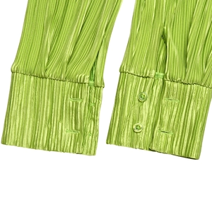 Detail of green ruffle sleeve cuff with button closure and textured crinkle fabric
