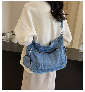 Detail shot of a blue denim tote bag featuring side pockets and a round coin purse charm