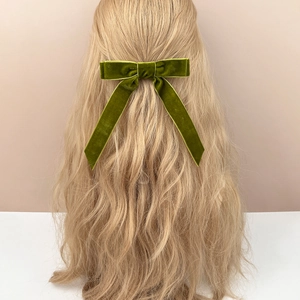 Detail of olive green velvet bow hair clip with long ribbons on wavy blonde hair