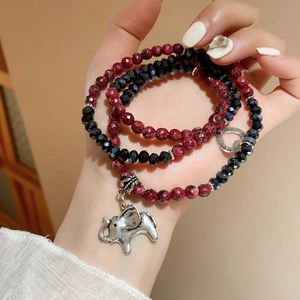 Detail of multi-layer beaded bracelet featuring red rhodochrosite and silver elephant charm