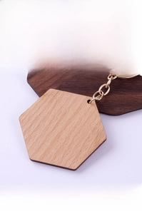 Macro detail of hexagonal beech wood keychain with gold ring and natural grain texture