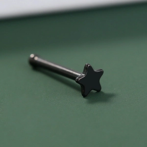 Macro shot of a black stainless steel star shaped nose stud piercing with straight bar detail