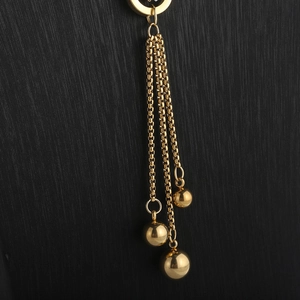 Detailed view of long gold tassel pendant with three box chains and spherical beads