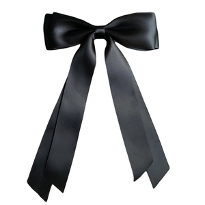 Macro detail of high-gloss black satin ribbon double-layer bow hair clip on white background