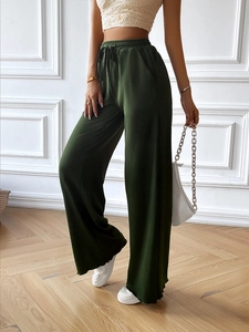 Detail of dark green wide-leg pants with vertical texture and drawstring waistband