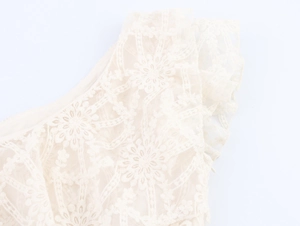Dettaglio del tessuto in pizzo bohémien beige con raffinati ricami floreali