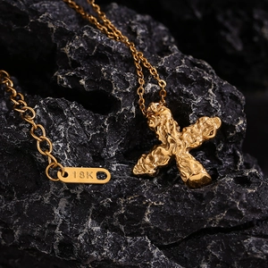 Macro view of 18K gold plated cross pendant with hammered texture on black stone