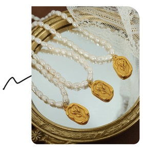 Detail of freshwater pearl necklace with gold tulip relief pendant on vintage mirror