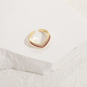 Detailed macro view of V-shaped gold ring featuring red gemstones and clear crystals