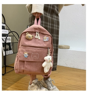 Detalle de mochila de pana rosa con bordado de oso y colgante de peluche suave