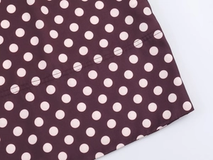 Detail eines Polka-Dot-Musters auf weinrotem Stoff mit sauberen Nähten und Textur
