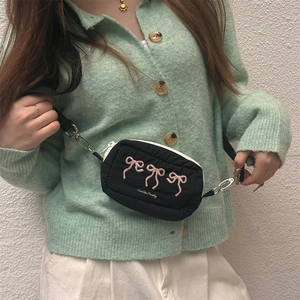 Detail of a quilted black crossbody bag featuring pink bow embroidery and a silver clasp