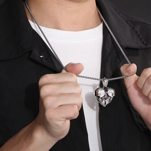 Close-up of punk style heart skull pendant with red gem on a stainless steel chain