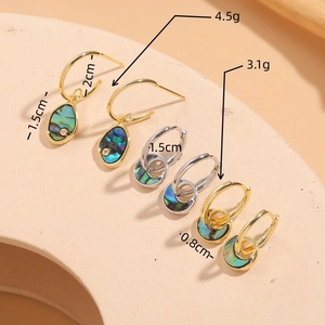 Elegant abalone shell and zircon earrings in gold and silver set on a warm display