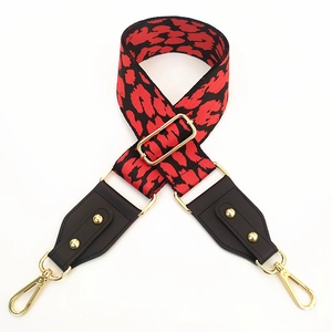 Detail of red and black leopard print wide bag strap with golden hooks and leather ends