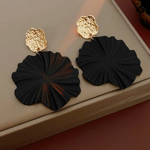 Close-up of geometric floral earrings with hammered gold and matte black petals