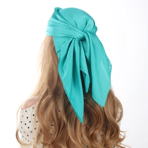 Detailed view of the emerald green satin square scarf drape on a woman's back