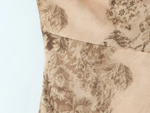 Detailed close-up showing vintage floral print and fine stitching on beige silk fabric