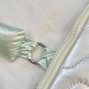 Detail of white quilted puffy laptop sleeve featuring a mint green metallic strap and ring