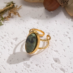 Vintage gold stainless steel ring with oval green natural stone on textured background