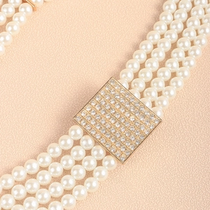Macro detail of multi-strand pearl belt with square gold buckle and crystal rhinestones