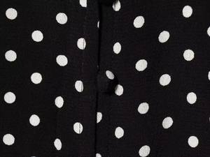 Dettaglio macro del tessuto a pois bianchi e del bottone rivestito su un abito nero