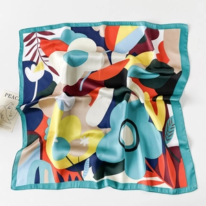 Detailed close-up of 70x70cm square silk scarf with abstract floral patterns and rolled edges