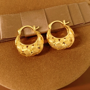 Macro shot of gold-plated U-shaped earrings with fine basket-weave texture detail