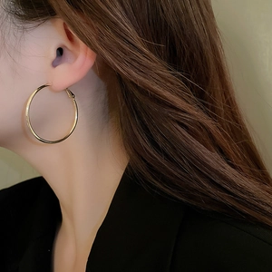 Model wearing minimalist gold hoop earrings showing the classic large circular design