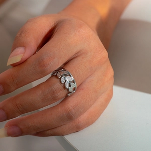 Detailed close-up of a silver titanium steel open ring with hollow leaf design