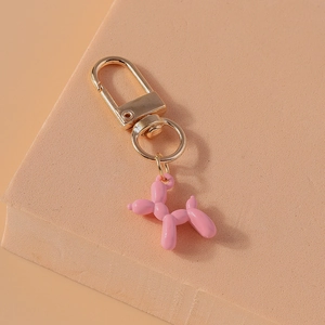 Detail of pink balloon dog keychain on artistic stand with gold-tone hardware