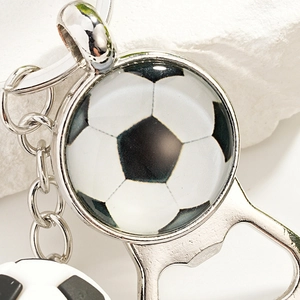 Macro detail of silver metal football bottle opener keychain on a stone surface