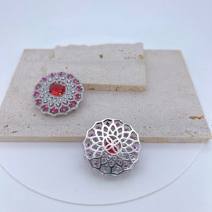 Macro detail of silver floral pendant featuring ruby red stones and intricate hollow back