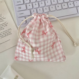 Pink checkered drawstring pouch with red bow patterns on a clean desktop scene