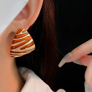 Close-up of vintage triangular earring with orange and cream zebra pattern on model