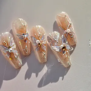 Macro shot of 3D butterfly nail charms and rhinestones on shimmering pink base art