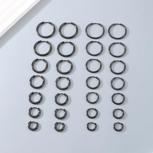 Multiple sizes of black titanium steel hoop earrings arranged in pairs on grey surface